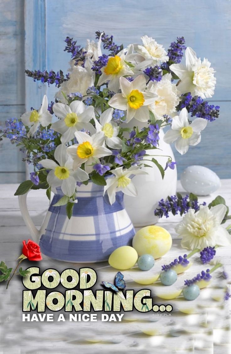 This may contain a blue and white vase filled with flowers next to an easter egg on a table