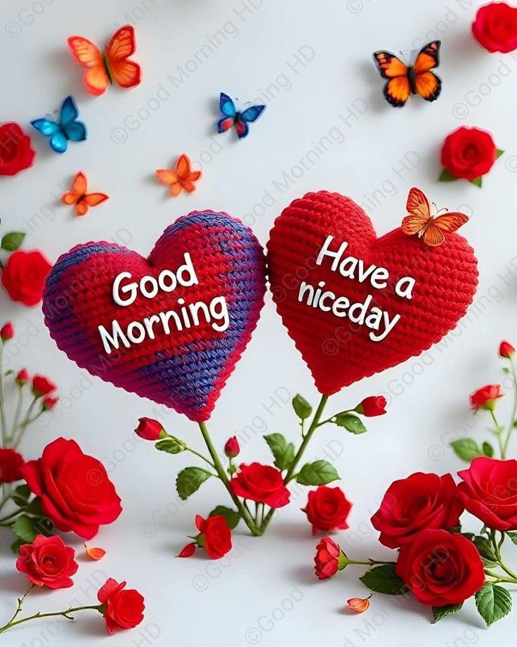 This may contain two crocheted hearts with good morning written on them surrounded by red roses and butterflies